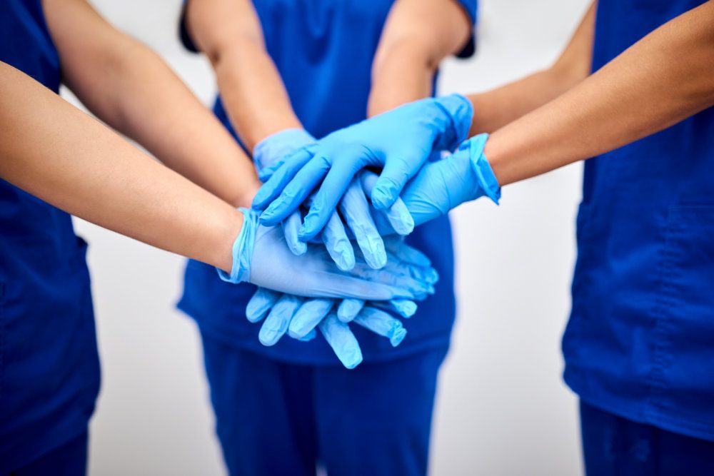 A team wearing blue medical scrubs and gloves