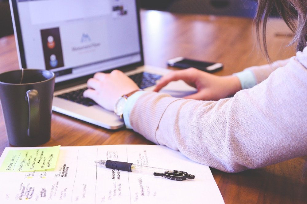 A woman using a laptop and taking notes